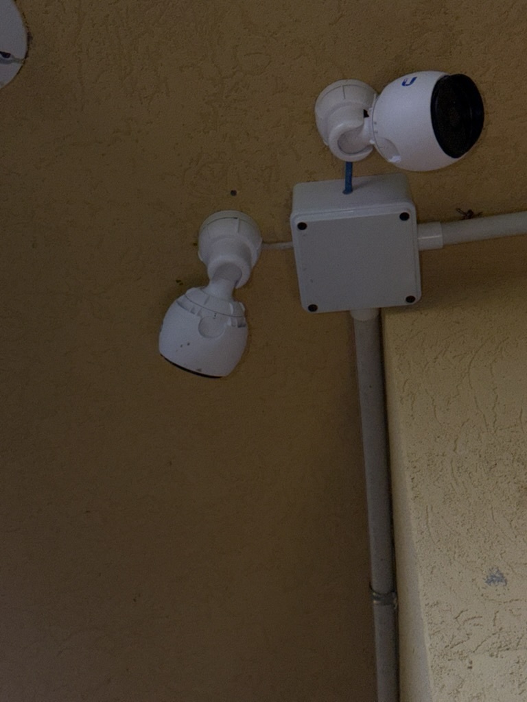 Two UniFi G3 Instant cameras mounted on exterior wall with junction box and conduit